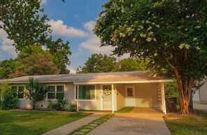 Ein eingeschossiges Haus mit Veranda, Garage und Rasen.