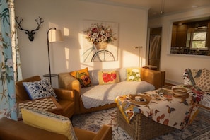 Ein gemütliches Wohnzimmer mit einer Couch, Sesseln, einem Couchtisch und einer Hirschdekoration an der Wand.