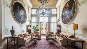Una sala imponente con pinturas decorativas, un candelabro y un gran tapiz.