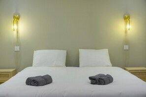 A double bed with white linens and two folded towels on the bed. - Townhouse Studio 2 Deluxe (Cannes)