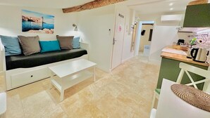 A modern living room with a sofa, a coffee table, and a kitchen area with a kettle and a microwave. - 1539891003 TOWNHOUSE STUDIO 2 (Cannes)