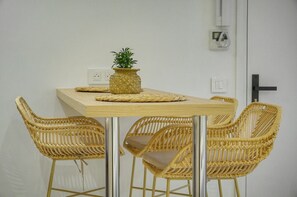 A dining area with a wooden table and four wicker chairs. - Townhouse Studio 2 Deluxe (Cannes)