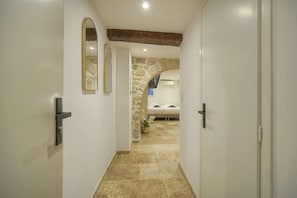 A hallway leading to a bedroom with a stone archway, a bed, and a bathroom with a sink and mirror. - One-bedroom apartment in France, Cannes (Cannes)