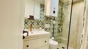Un baño con inodoro, lavamanos y ducha.