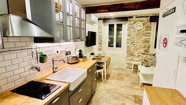 Una cocina moderna con estufa integrada, pileta y alacenas. Hay una zona de comedor con mesa y sillas.