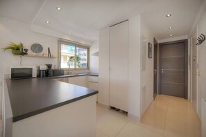 A modern kitchen with a central island, a window, and a door leading to another room. - 15099954 `Palm Beach Luxury 1-Bedroom Apartment with Balcony, AC` (Cannes)