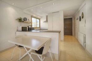 A modern kitchen with a white countertop, a dining table, and a built-in microwave. - 15099954 `Palm Beach Luxury 1-Bedroom Apartment with Balcony, AC` (Cannes)
