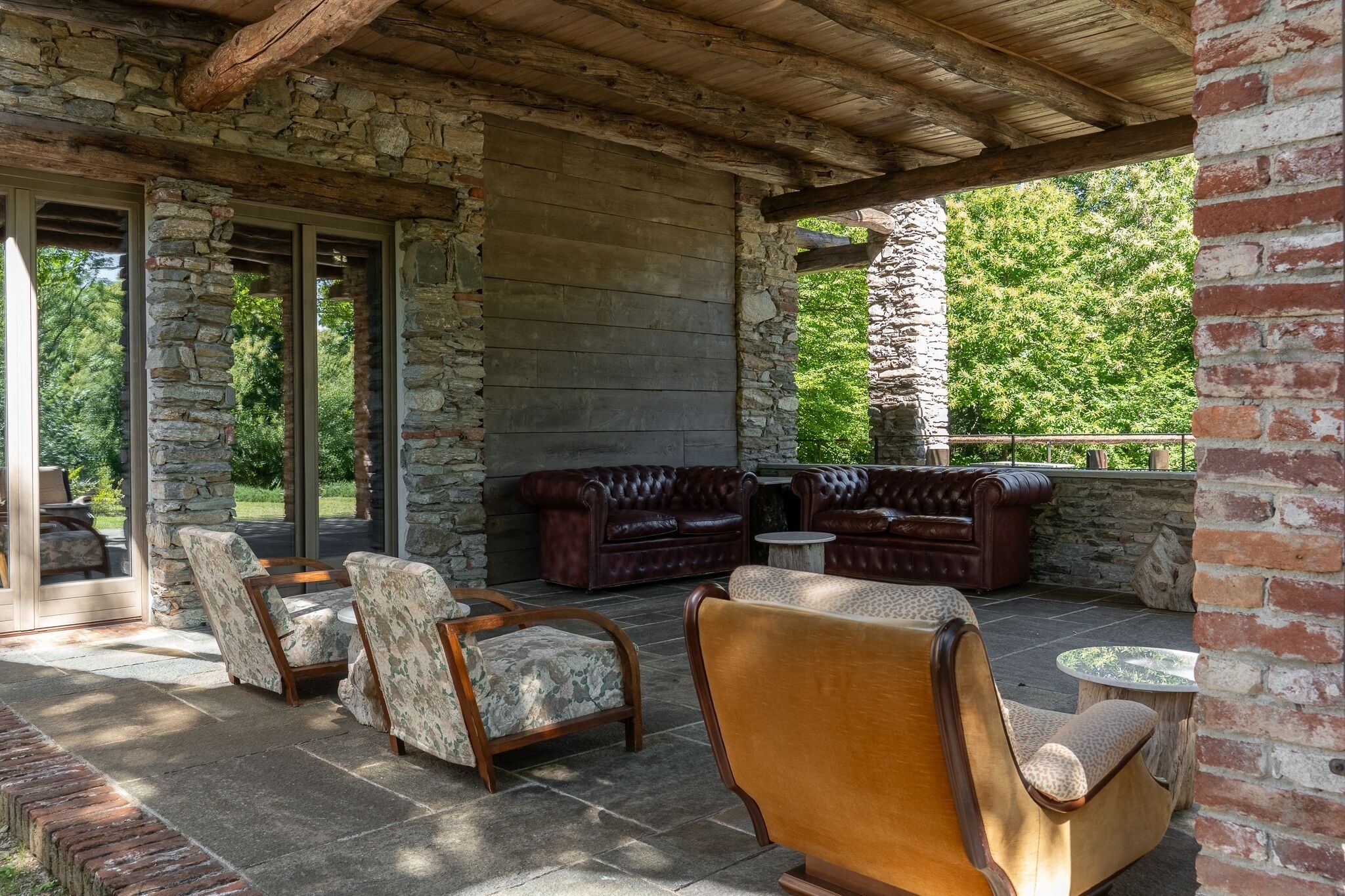 Une terrasse extérieure avec des murs en pierre, un plafond en bois et des meubles en cuir.