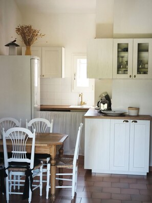 A kitchen with white cabinets, a wooden table, and chairs. - Fully Equipped 2-Bedroom Apartment in the Gulf of St. Tropez (Cogolin)