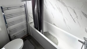 A bathroom with a bathtub, toilet, and towel rack.