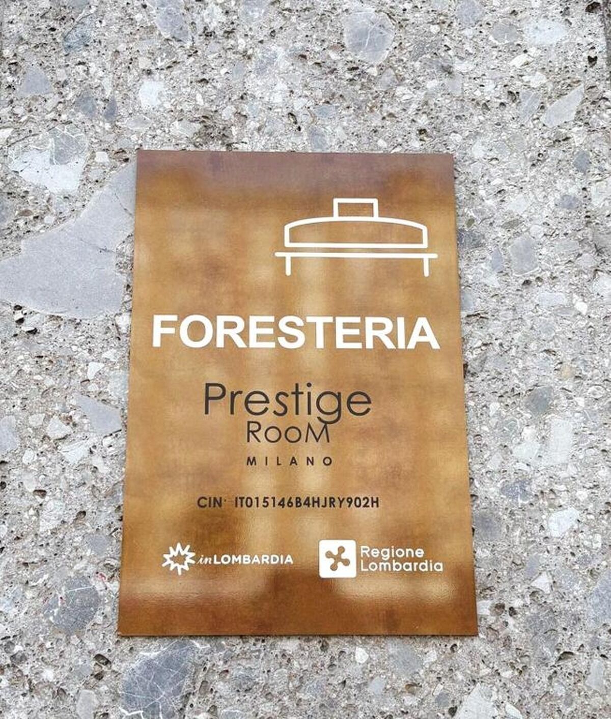 Une enseigne pour un hôtel nommé « FORESTERIA Prestige Room » à Milan, avec les coordonnées et les logos de « inLombardia » et de la « Région de Lombardie ».