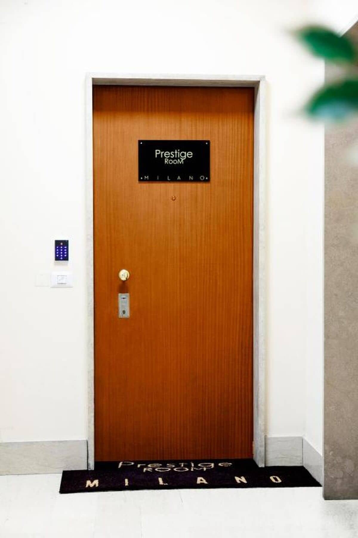 Une porte en bois sur laquelle est apposée une plaque indiquant « Prestige Room » et, en dessous, le mot « MILANO ».