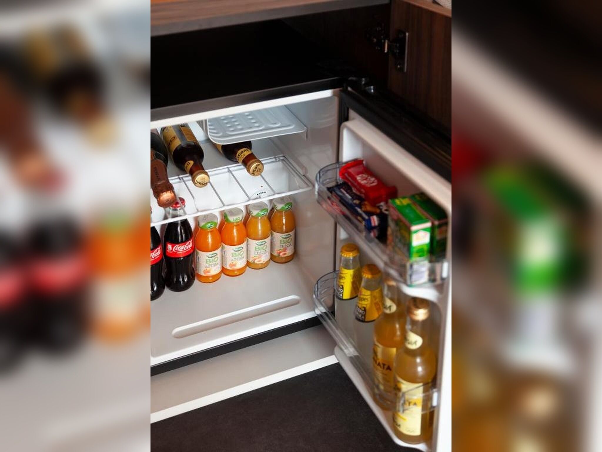 Un refrigerador abierto con varias bebidas y condimentos.