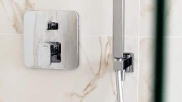 Eine Dusche mit chromfarbenem Wasserhahn und einer wandmontierten Armatur.