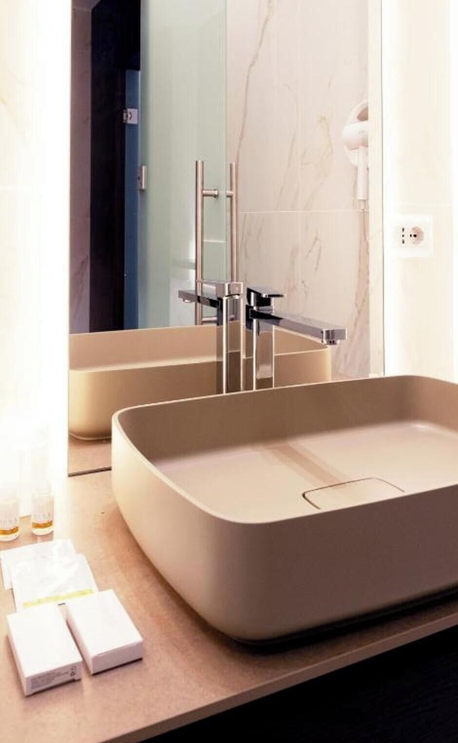 Ein modernes Badezimmer mit einem großen rechteckigen Waschbecken, einem Spiegel und einer Duschkabine.