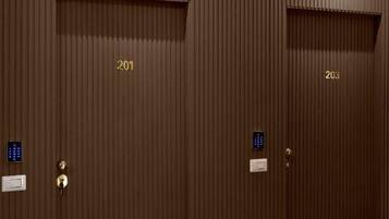 Conjunto de portas duplas com fechadura eletrônica por teclado numérico, identificadas com os números 201 e 203, em um cômodo com piso escuro.