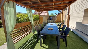 Een terras buiten met een tafel, stoelen, een houten pergola en een stenen muur.