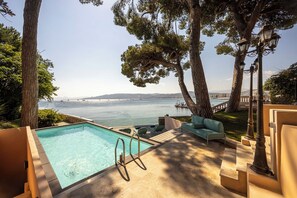 A pool area with a view of the sea, outdoor furniture, and trees. - Villa Sud, luxury villa with sea views on Cap d’Antibes. (Antibes)