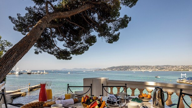 Una mesa lista para el desayuno con vista al mar y a los barcos.