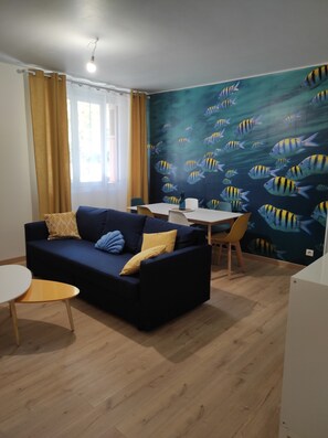 A living area with a sofa, a small round table, a dining table with chairs, and a wall mural of fish. - Sweet Stay, air conditioning, parking, alarm system, all kinds of shops (Toulon)