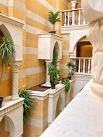 A courtyard with arches, columns, and potted plants.