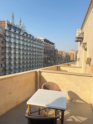 A rooftop terrace with a table and chairs, overlooking a densely packed urban area with high-rise buildings. - The Grand Delta Hotel (Giza)