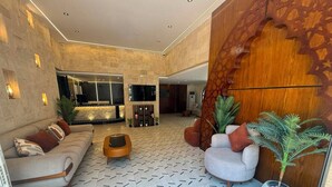 Un vestíbulo amplio con piso estampado, un sofá, una mesa de centro y una gran pared de madera decorativa.