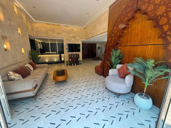 A spacious lobby with a patterned floor, a sofa, a coffee table, and a large wooden accent wall. - The Grand Delta Hotel (Giza)