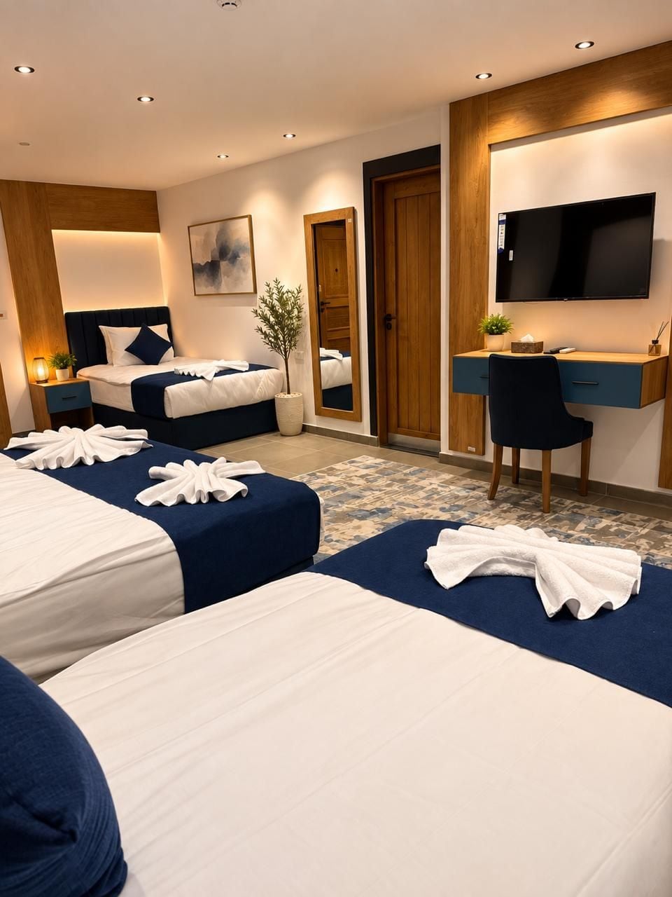 Habitación de hotel con dos camas, un escritorio, un televisor y una planta.