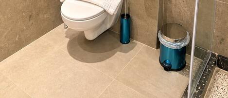 A modern bathroom with a toilet, a shower, and a glass-enclosed shower stall.