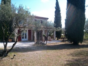 A building with a red door, a satellite dish, and a gravel driveway. - COTTAGE LES OLIVIERS AT COTIGNAC (Cotignac)