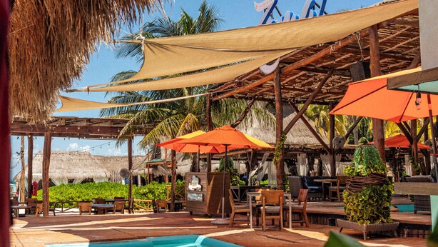 A pool area with wooden deck, umbrellas, and thatched roof structures. - Hotel Isla Mujeres Centro (Isla Mujeres)