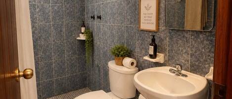Un baño con inodoro, lavamanos, ducha y espejo.