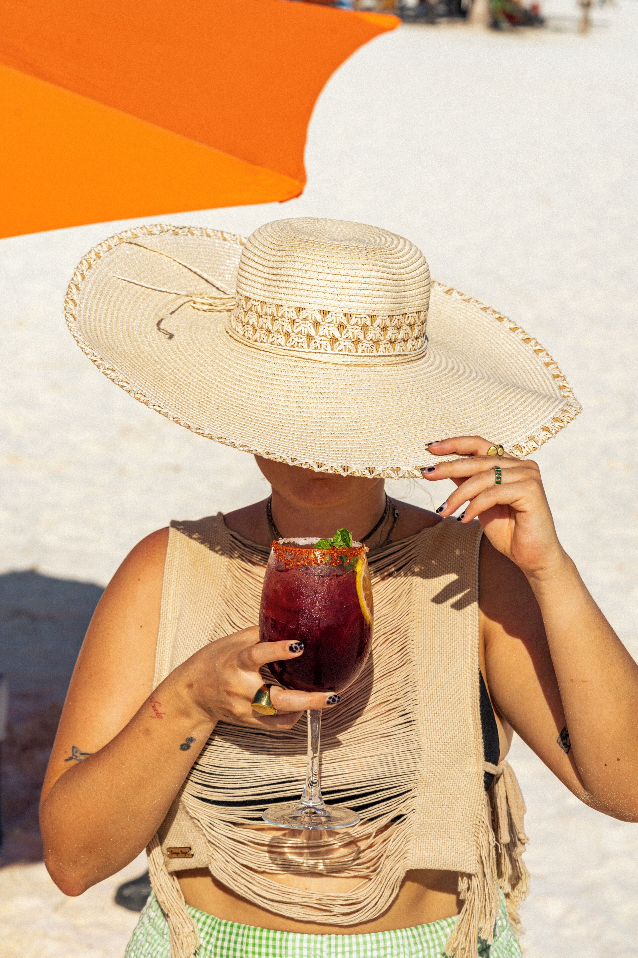 A person wearing a straw hat and holding a drink.