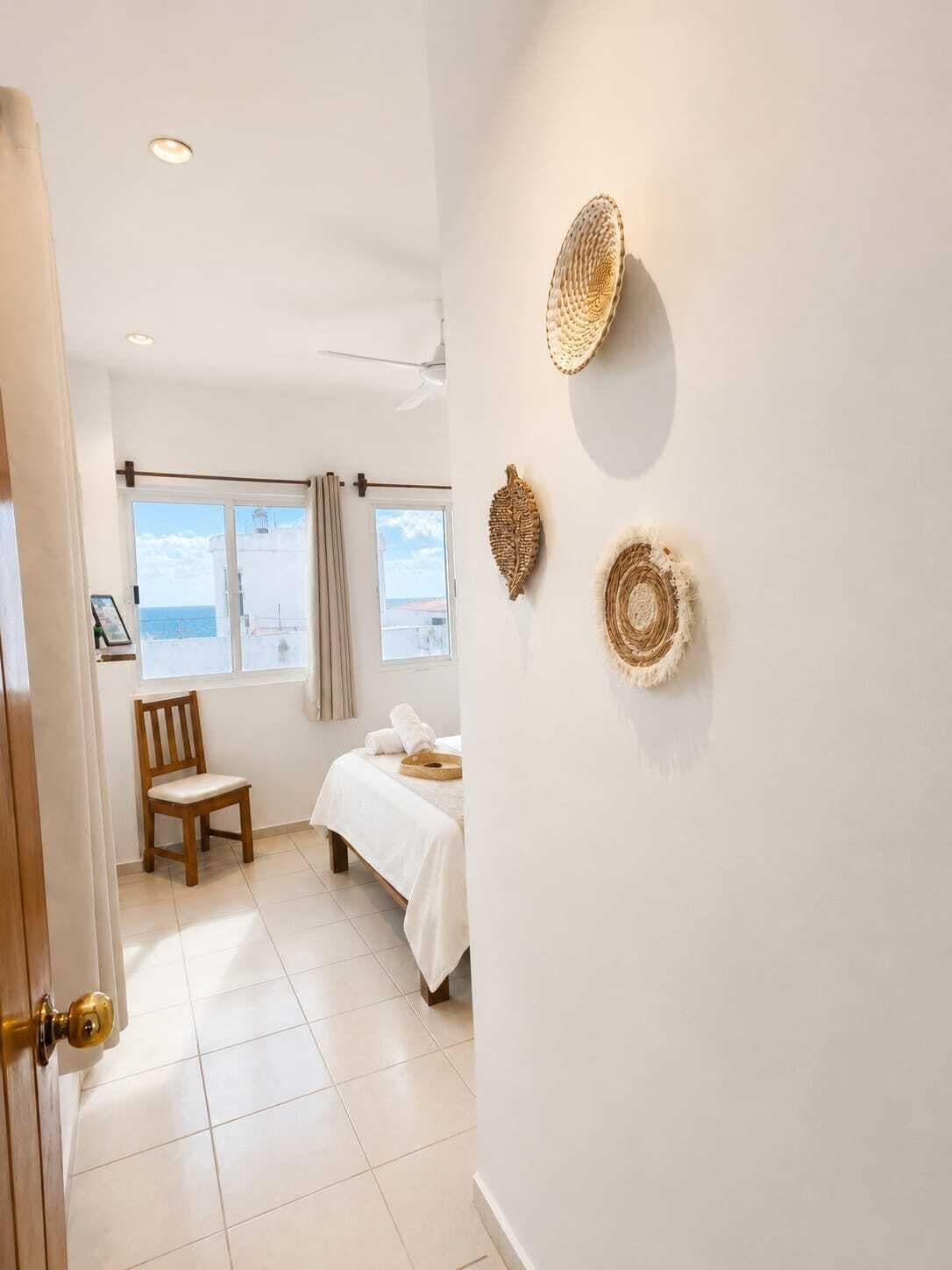 A room with a bed, a chair, a window with curtains, and wall decor.