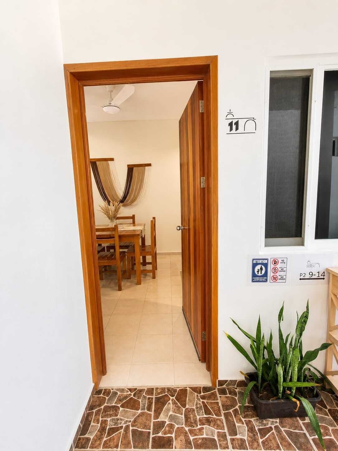A doorway leading to a dining area with a table and chairs, a potted plant, and a window with a view.