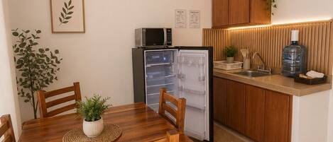 A compact kitchen with a microwave, refrigerator, wooden cabinets, and a dining area with a table and chairs.
