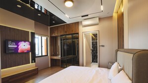 Una habitación de hotel moderna con una cama grande, un televisor montado en la pared y un armario con puerta corredera.