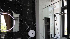 Un baño moderno con salpicadero de mármol, inodoro, ducha y tocador con espejo.