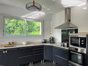 Eine moderne Küche mit großem Fenster, einem eingebauten Backofen und einer Edelstahl-Dunstabzugshaube.