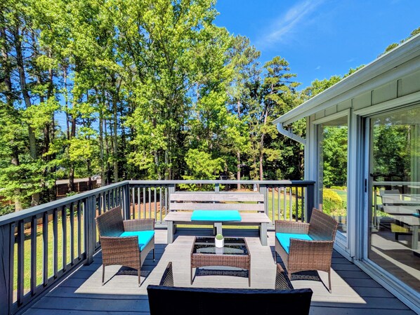 A deck with outdoor furniture, a glass door, and a view of trees.