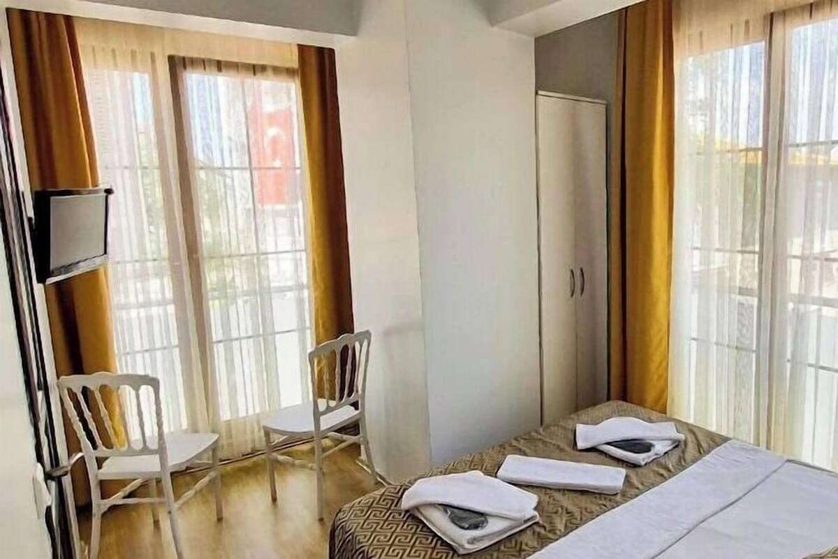 Una habitación de hotel con cama, una silla, televisor y armario.