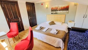 Quarto de hotel com cama, duas cadeiras, escrivaninha e guarda-roupa.