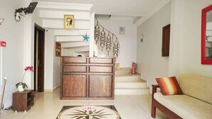 Uma sala de estar com sofá, armário de madeira, escada e tapete decorativo.