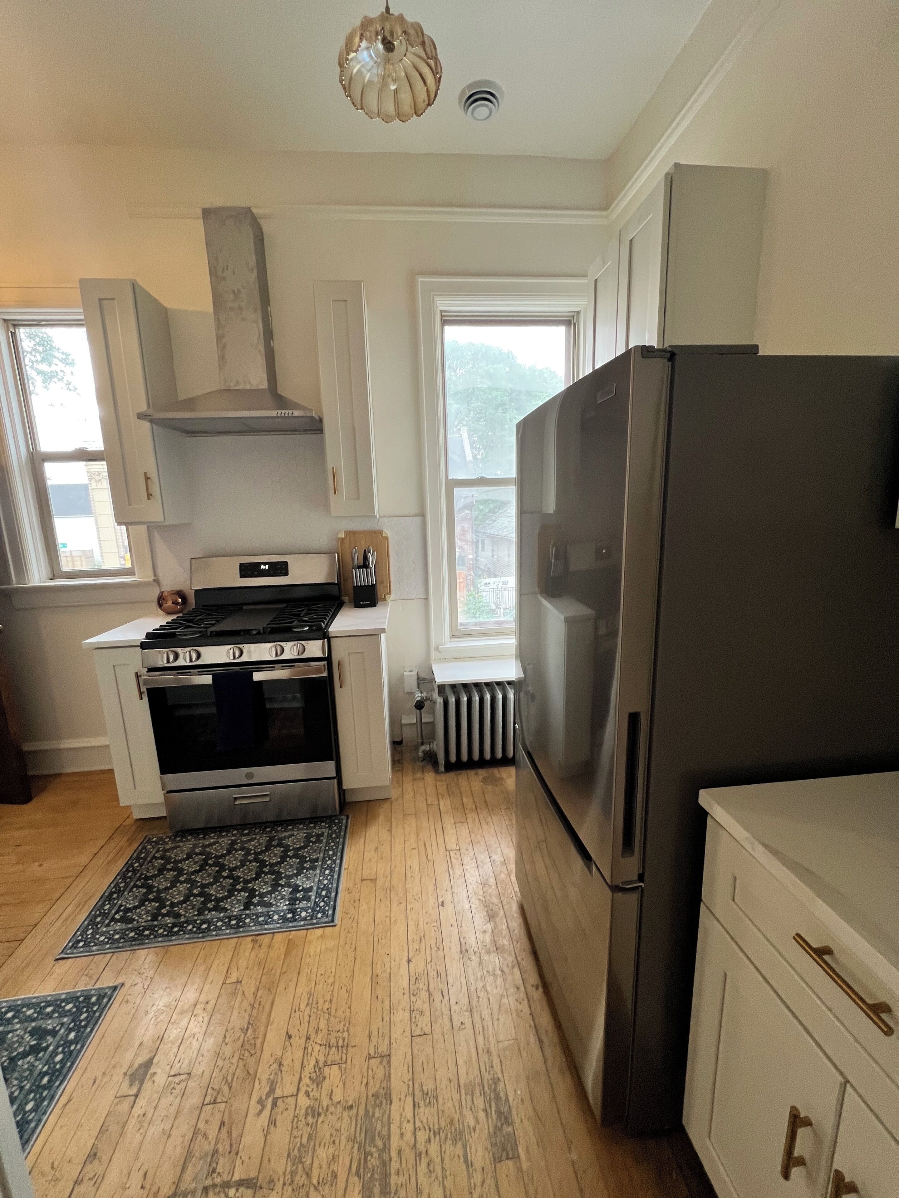 Una cocina con estufa, horno, refrigerador y ventana con vista a vegetación.
