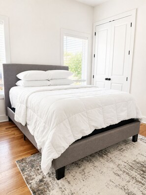 A bedroom with a bed, a window with blinds, a door, and a rug. - Spacious 4-bedroom house in tranquil Atlanta with AC (Atlanta)
