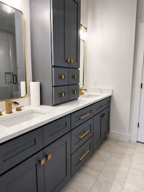 A modern bathroom with a large mirror, two sinks, and dark grey cabinets with gold handles. - Spacious 4-bedroom house in tranquil Atlanta with AC (Atlanta)
