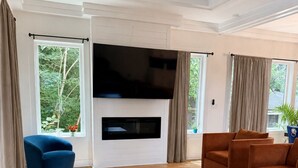 Una sala de estar con televisión de pantalla plana, ventilador de techo y chimenea.
