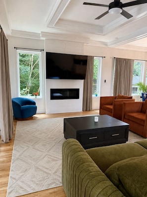 A living room with a flat-screen TV, a ceiling fan, and a fireplace. - Spacious 4-bedroom house in tranquil Atlanta with AC (Atlanta)