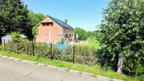 A single-story house with a sloped roof, a visible chimney, and a fenced yard. - Villa with Air Conditioning, Netflix, and a Pool (Blegny)